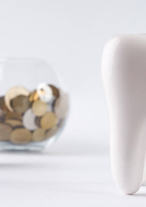 tooth next to a bowl of coins